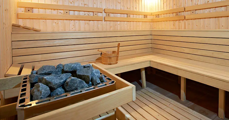 Large Sauna with benches and heater with a lot of rocks stacked on it
