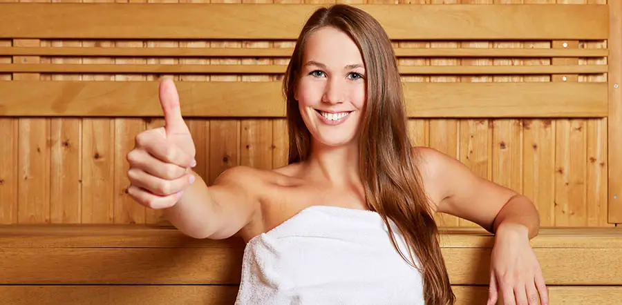 Woman in sauna holding thumbs up