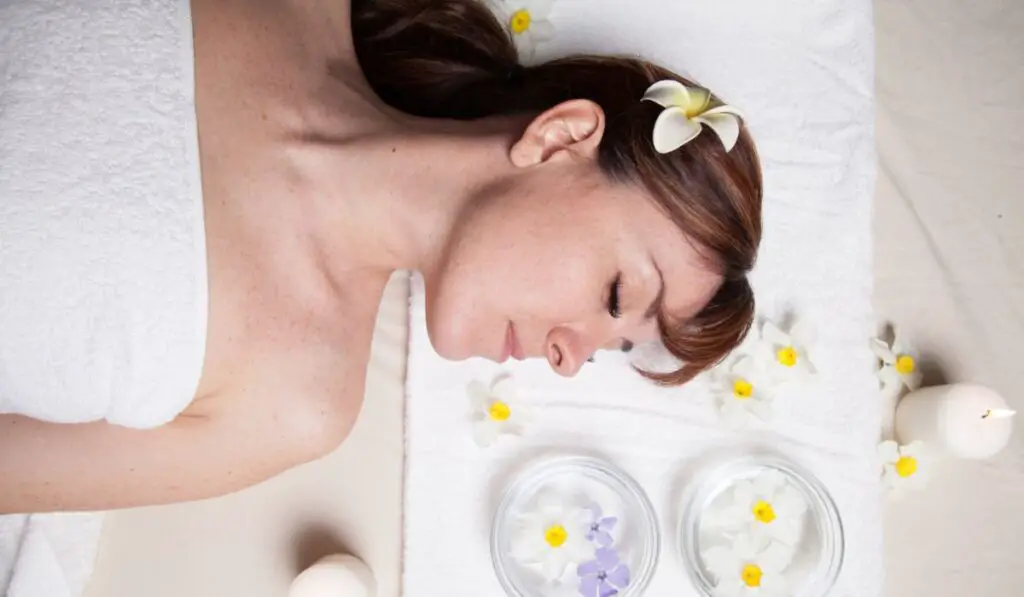 Attractive young girl lying with closed eyes in sauna