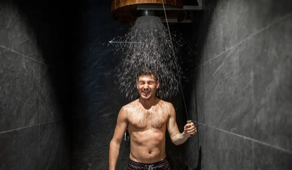 Man hardening with bucket of ice cold water after hot sauna