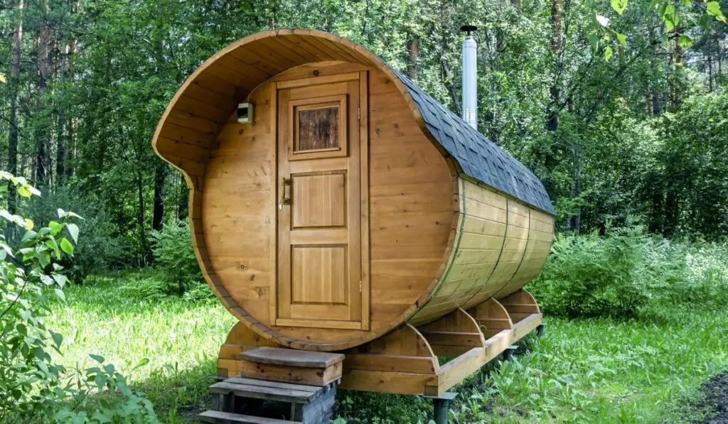 Round wooden barrel bath stands in the forest on a summer day