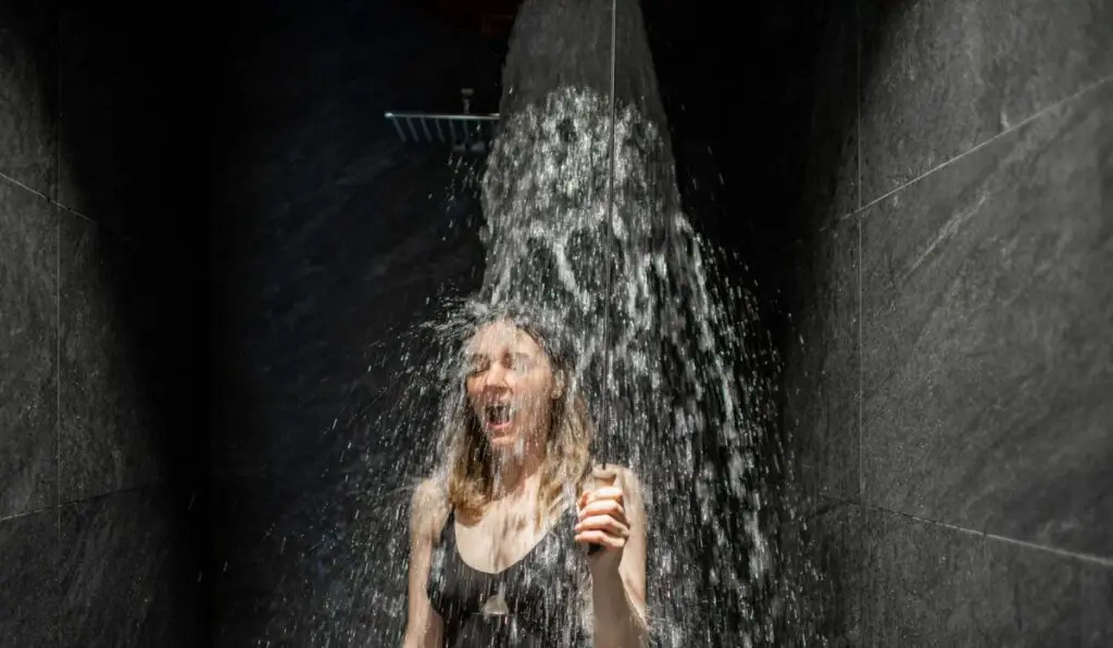 Woman hardening with bucket of ice cold water after hot sauna