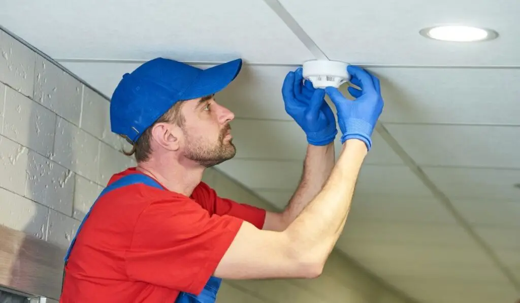 Worker installing smoke detector on the ceiling 