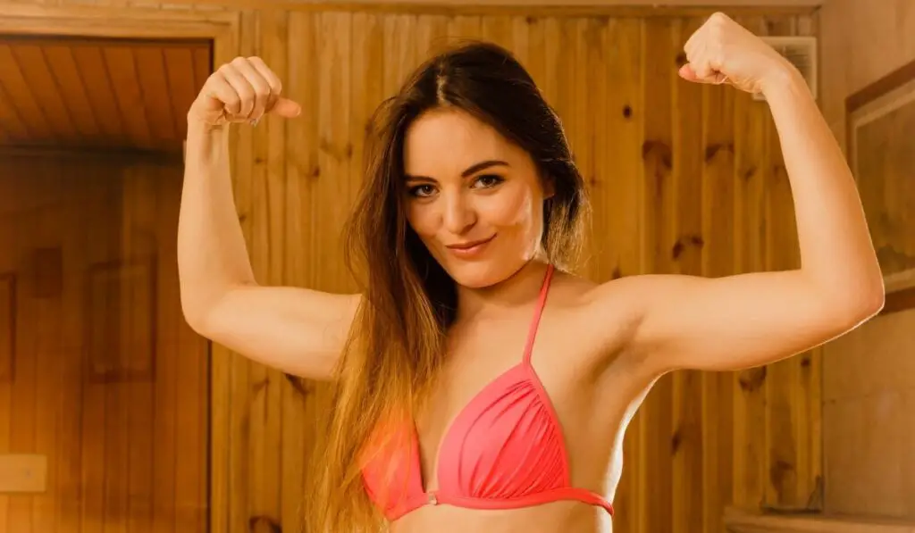 Woman relaxing in sauna showing off muscles